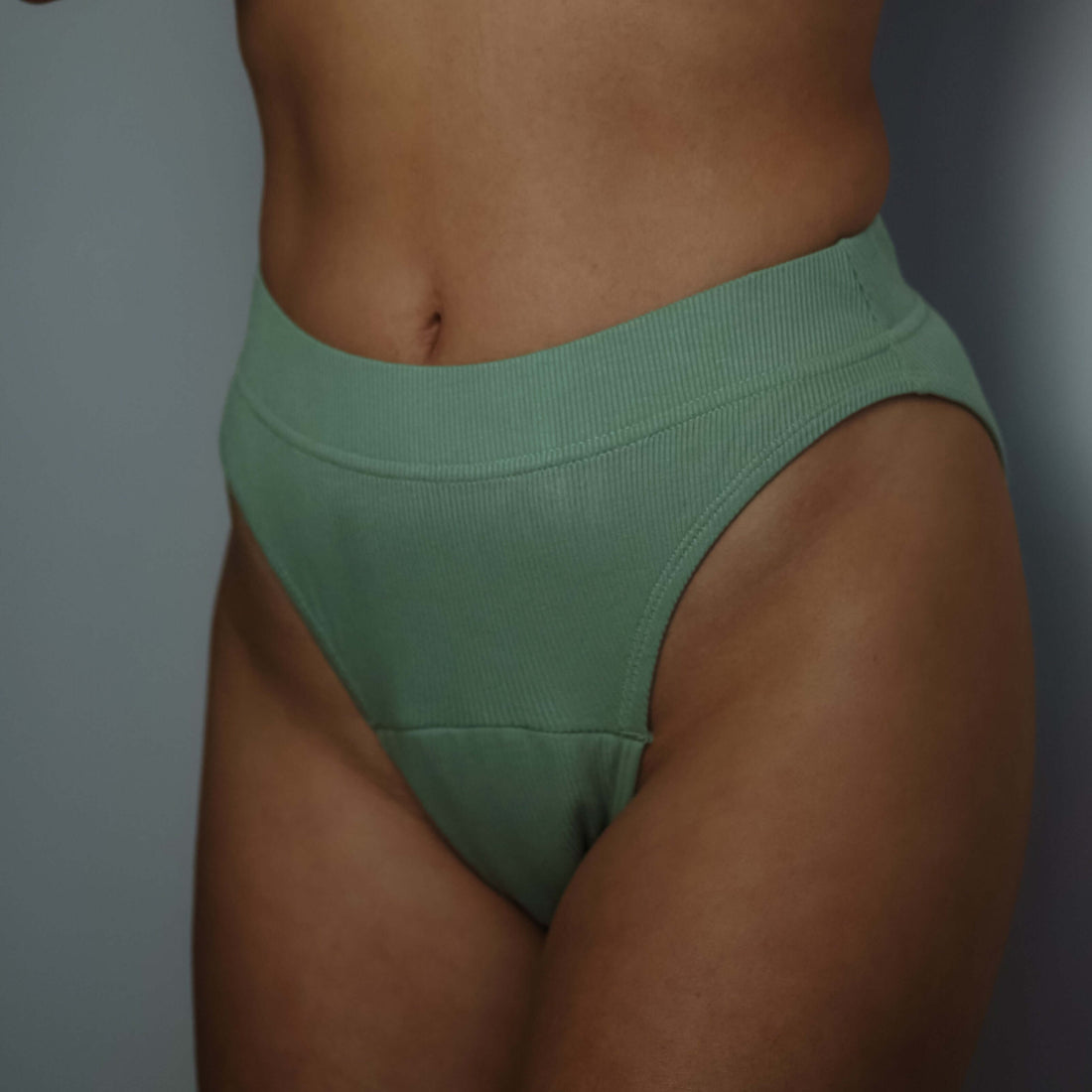 Woman wearing green high-leg period underwear offering breathable comfort and sustainable protection.